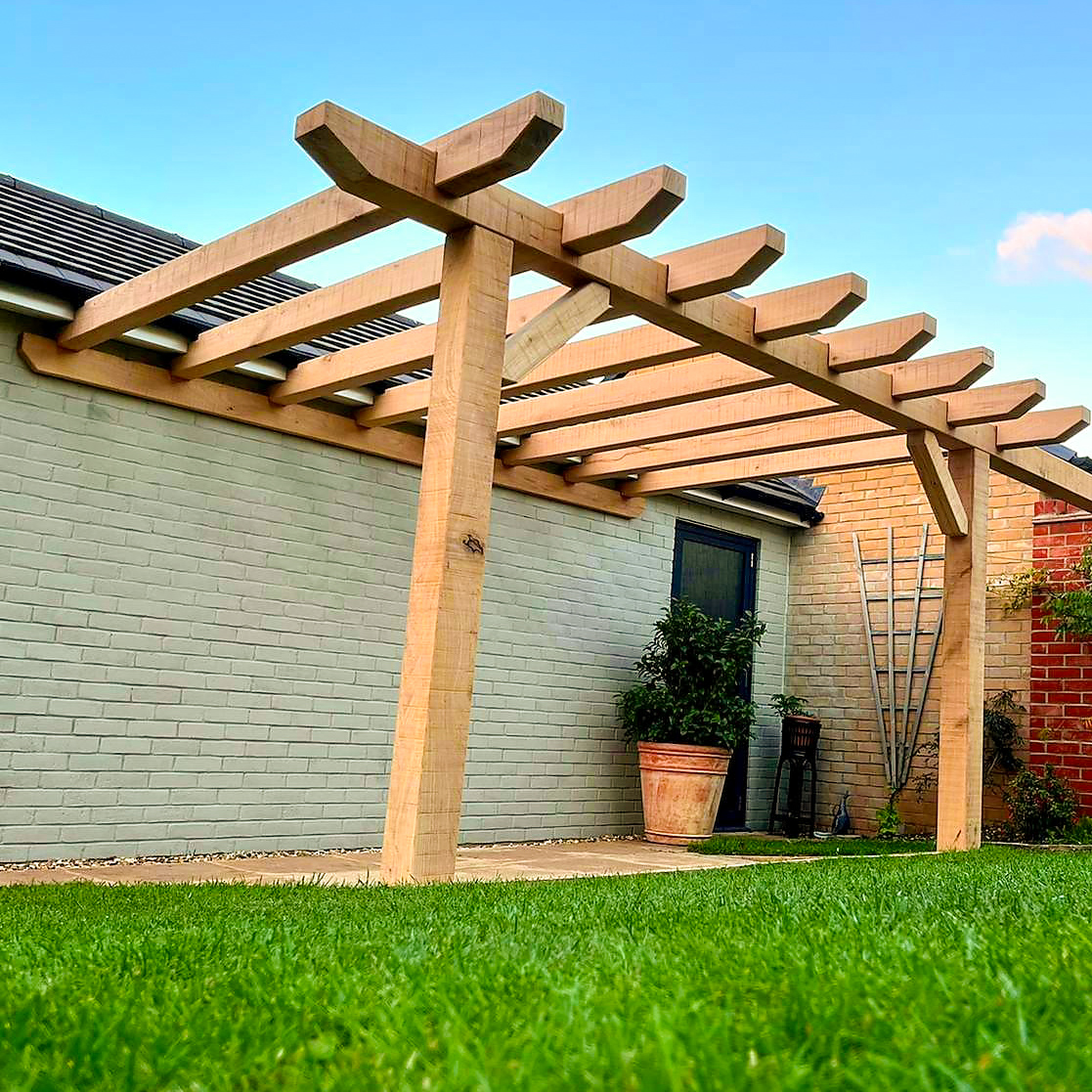 Contemporary oak pergola integrated beside a garden wall near Stamford.